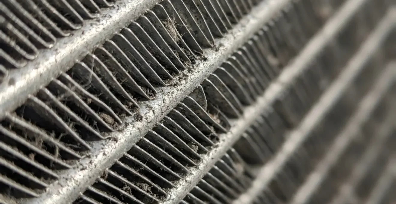 Gros plan sur les ailettes d'un condenseur d'armoire réfrigérée avec accumulation de poussière visible